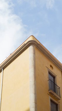 Barselona, İspanya 'daki sarı-turuncu konutun köşesinin alçak açılı görüntüsü. Bir pencerenin ve arkadaki mavi gökyüzünün ayrıntıları