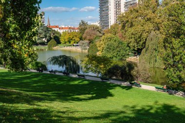 Parisliler sonbaharın başlarında güneşli bir günde Parc Montsouris gölünün kıyısında güneşleniyorlar.