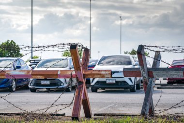 Otoparkın dikenli telleri. Arabalar açık hava otoparkına park edilmiş. Bir kredi şirketi tarafından arabaya el konuldu. Araba kredisi üzerinde mali kriz etkisi. Kullanılmış araba işi. Otomobil kiralama ve sigorta.