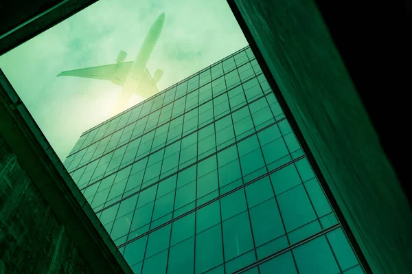 底部可以看到现代化的玻璃办公楼 上面有一架飞机在飞行 摩天大楼的外立面 公务旅行 金融中心 航空业 透明玻璃窗 — 图库照片