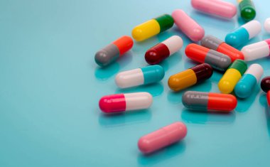 Mavi arka planda antibiyotik kapsül hapları. Reçeteli ilaçlar. Renkli kapsül hapları. Antibiyotik ilaç direnci konsepti. İlaç sanayisi. Süper böcek problemleri. Medicament ve farmakoloji.