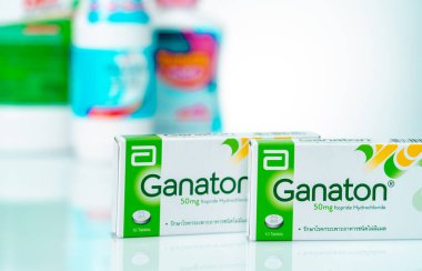 CHONBURI, THAILAND-NOVEMBER 22, 2021 Abbott Laboratuvarları 'nın Ganaton ürünü. Bulanık ilaç şişelerinin arka planında karton kutudaki Ganaton tabletleri. Ülser olmayan hazımsızlık için reçete yazılıyor..