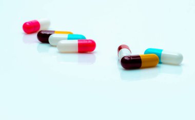 Multi-color antibiotic capsule pills spread on white background. Antibiotic drug resistance. Antimicrobial capsule pills. Pharmaceutical industry. Pink, white, blue, yellow, and red capsule pills.