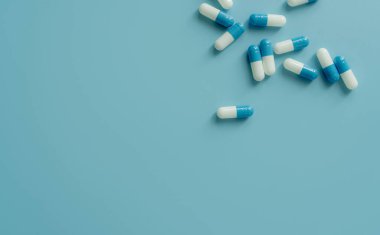 Top view blue-white antibiotic capsule pills on blue background. Prescription drug. Antibiotic drug resistance. Pharmaceutical industry. Pharmaceutical care. Pharmaceutics concept. Antimicrobial drug.