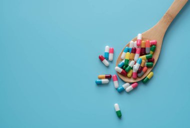 Antibiotic capsule pills on spoon and blue background. Antibiotic drug resistance. Pharmaceutics. Medical health care. Prescription drugs. Drug use problems. Dose of medicine. Pharmaceutical care.