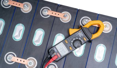 Electric vehicle lithium NMC battery. Electric car battery. Lithium-ion cell pack. Lithium NMC rechargeable battery. EV car energy storage. Multimeter measuring volts of electric vehicle battery.