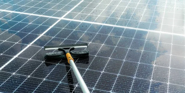 Cleaning solar panel with microfiber mop on wet roof. Solar panel or photovoltaic module maintenance service. Sustainable resource. Solar power. Green energy. Sustainable development technology.
