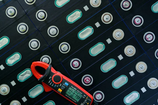 Electric vehicle lithium NMC battery with multimeter. Electric car battery manufacturing factory. Lithium-ion cell. Lithium NMC rechargeable battery. EV car energy storage. Automotive battery cell.