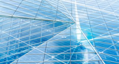 Sustainable glass building and wind power concept. Wind turbine and blue sky reflect on sustainable corporate office building. Green energy. Sustainable development goals concept. Renewable energy.