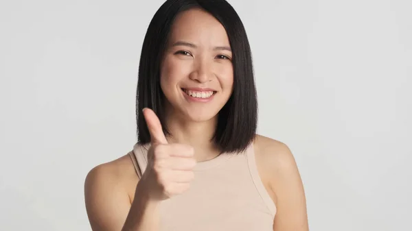 Pozytywna Azjatka Trzymająca Kciuk Szarym Tle Azji Dziewczyna Uśmiecha Się — Zdjęcie stockowe