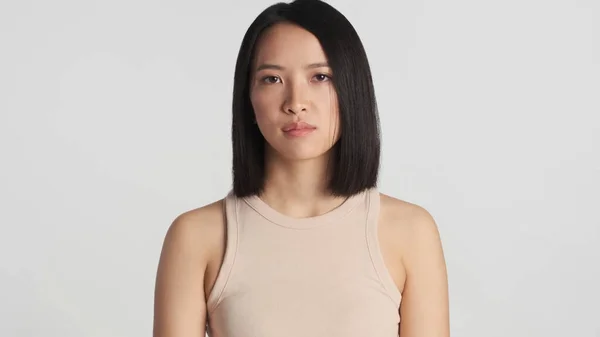 Nuori Kaunis Aasialainen Nainen Tarkkaavaisesti Katselee Kameraa Valkoisen Taustan Yläpuolella — kuvapankkivalokuva