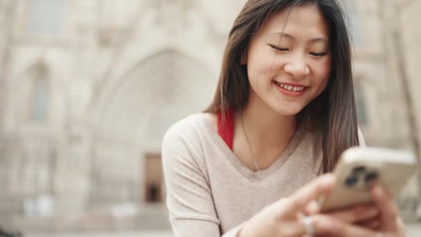 머리의 아시아 소녀가 스마트폰을 확인하면서 행복해 보이는 계단에 — 비디오