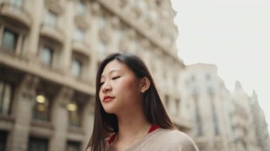 Çekici, uzun saçlı, sıradan giyinmiş Asyalı kadın. Sokakta yürürken düşünceli görünüyor.