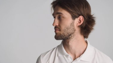 Beyaz arka planda reklam ya da terfi için yer arayan sakallı genç bir adam. Çekici adam fotokopi alanının yanında duruyor.