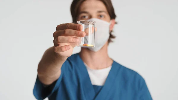 Mężczyzna Lekarz Noszący Maskę Medyczną Pokazującą Tabletki Szklanej Kolbie Przed — Zdjęcie stockowe