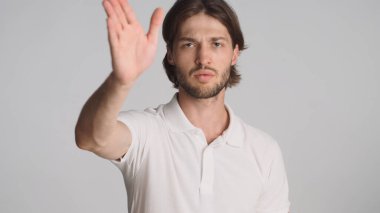 Kızgın görünen genç adam, iş yerindeki kararla beyaz arka plan üzerinde fikir ayrılığına düşüyor. Ciddi bir adam stüdyoda duruyor.