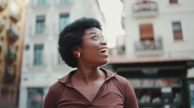 Heyecanlı, koyu renk saçlı, gözlüklü Afrikalı bir kadının fotoğrafını çekiyorum. Şaşırmış Afrikalı kız mutlu görünüyor, tek başına yeni şehri keşfediyor.