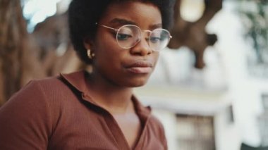 Gözlüklü Afrikalı Amerikalı bir kızın açık havada kitap okumaya vakit ayırdığı portresi. Açık havada okuyan koyu renk saçlı genç bir kız öğrenci.