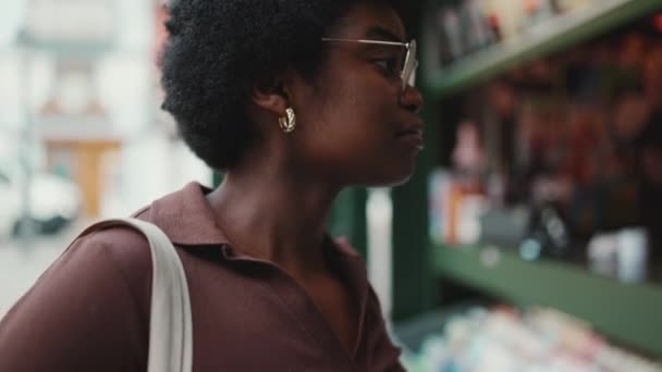Widok Boku Strzał Afrykańskiej Dziewczyny Okularach Wybierając Magazyn Kiosku Ulicy — Wideo stockowe