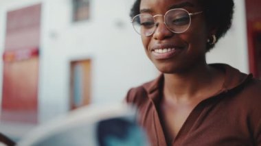 Neşeli Afrikalı kızın ilginç bir kitap okuyup dışarıda eğlendiği yakın çekim. Mutlu yüz ifadesi