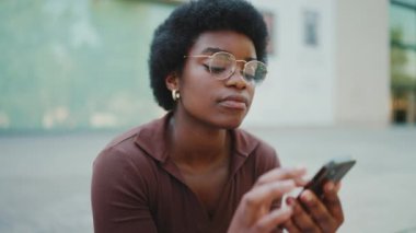 Gözlüklü Afrikalı kızın portresi sokakta akıllı telefon kullanarak arkadaşına sesli mesaj kaydediyor. Modern teknoloji