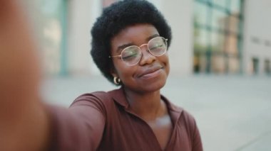 Çekici esmer tenli kadın sokakta selfie çekerken hava öpücüğü veriyor. Genç Afrikalı kadın kameraya gülümsüyor