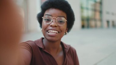 Dışarıdaki sosyal medyası için jest videosu gösteren Afrikalı bir kadın portresi. Afrikalı blogcu kız başparmağını kaldırıyor ve kameraya hava öpücüğü gönderiyor