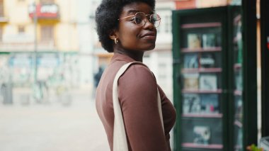 Güzel esmer kadın açık havada rüya gibi görünüyor, gözlük takıyor. Esmer tenli kız sokakta dikiliyor..