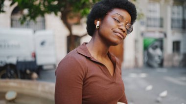 Gözlüklü şehvetli bir Afro-Amerikan kadının portresi kulaklıkları kapalı güzel bir şarkı dinliyor. 