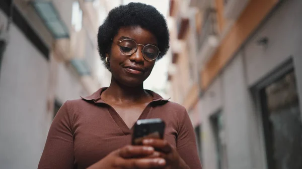 Joven Afro Chica Usando Gafas Texto Teléfono Inteligente Mujer Revisando — Foto de Stock