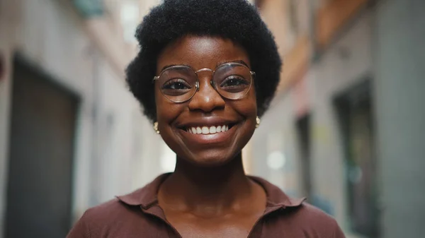 在外面用眼镜把快乐的非洲女人紧紧地抱在一起 对着相机真诚地微笑 无忧无虑的黑皮肤姑娘站在街上 看上去很快乐 — 图库照片