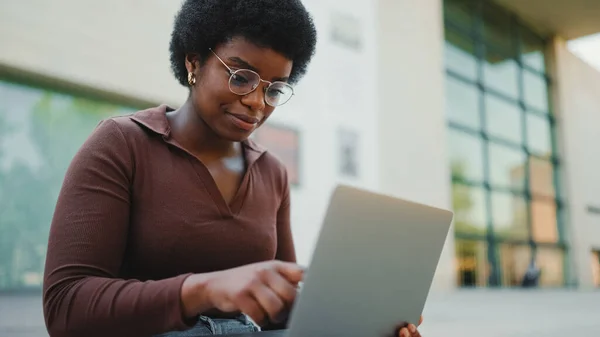 女性起業家がラップトップで屋外で働いています アフリカ系アメリカ人の女性が路上でラップトップで勉強している — ストック写真