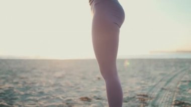 Güzel bir kadının sabahın köründe plajda yoga yaparken yakın çekim görüntüsü. Yogi kızı dışarıda çalışıyor.