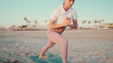 Deniz kenarında yoga yaparken sportif kızın dengesini korurken yakın çekim. Spor giyim kuşamında güzel bir kadın dışarıda egzersiz yapıyor.
