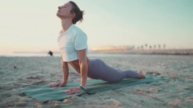 Dışarıda yoga minderiyle egzersiz yapan güzel bir kadın. Spor elbiseli kız formda kalmak için yoga yapıyor. Sahilde yoga.