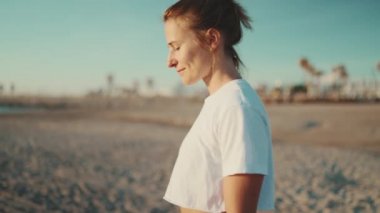 Kumsalda yoga yaptıktan sonra kendini iyi hisseden güzel sarışın kadın. Sportif kız idmandan sonra deniz kenarında yürüyor.