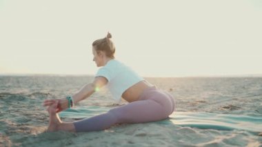 Sabah yogası sırasında açık havada sicim esneten güzel bir yoga kızı. Çekici bir kadın yoga yapıyor. Sahilde yeteneklerini geliştiriyor.