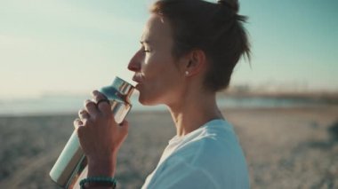 Sarışın güzel bir kadının sahilde sabah yogasının tadını çıkarırken çekilmiş yakın plan fotoğrafı. Sportif dövmeli kız deniz kenarında dinleniyor.