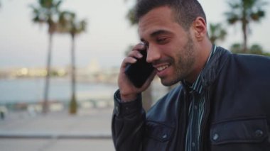 Gündelik giyinmiş genç işadamını kapat. Akşam sokakta akıllı telefondan konuşurken kendinden emin bir şekilde iş hakkında konuş.