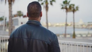 Yakışıklı esmer adamın akşam vakti şehirde yalnız yürürken çekilmiş görüntüsü.