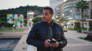 Kız arkadaşını dışarıda beklerken dalgın görünen esmer bir adamın portresi. Akşam caddesinde duran akıllı telefonu kullanan yakışıklı adam.