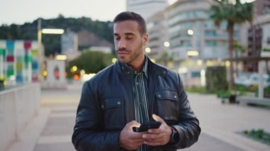 Genç esmer adam dışarıda kız arkadaşını beklerken akıllı telefon kullanırken dalgın görünüyor. Çekici bir adam akşam kentinde tek başına yürüyor.