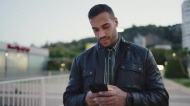 Esmer adamın akşam arkadaşlarıyla buluşacağından emin bir görüntüsü. Çekici adam telefonunu kontrol ediyor. Sokakta tek başına yürüyor.