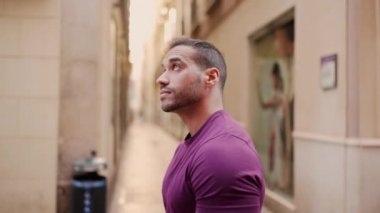 Yakışıklı, kaslı bir adamın dar sokakta yürürken rahat görünüşünün yan görüntüsü.