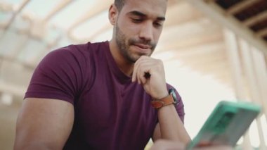 Yakışıklı bir adam sosyal medyasını kontrol etmek için açık havada akıllı telefon kullanıyor. Uzak iletişim