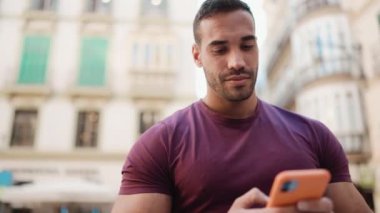 Şehir merkezinde duran ve akıllı telefonunu iletişim için kullanan çekici bir adam. Dışarıda cep telefonu kullanan sıradan giyinmiş genç bir adam.
