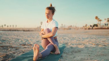 Profesyonel yoga öğretmeni sabahları sahilde yoga antrenmanı yapıyor. Tozluklu Yogi kızı dışarıda yoga yapıyor.