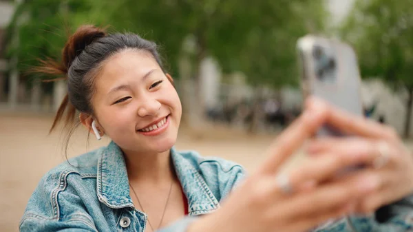 Attraktiv Asiatisk Jente Med Trådløse Øretelefoner Som Tar Selfie Smarttelefonen – stockfoto