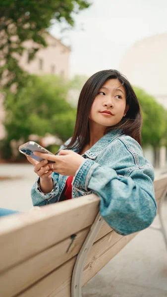 Retrato Cabelos Longos Menina Asiática Vestida Casual Sentado Banco Verificando — Fotografia de Stock