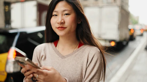 Melko Aasialainen Pitkätukkainen Tyttö Tekstailee Parhaan Ystävän Kanssa Älypuhelimella Kadulla — kuvapankkivalokuva